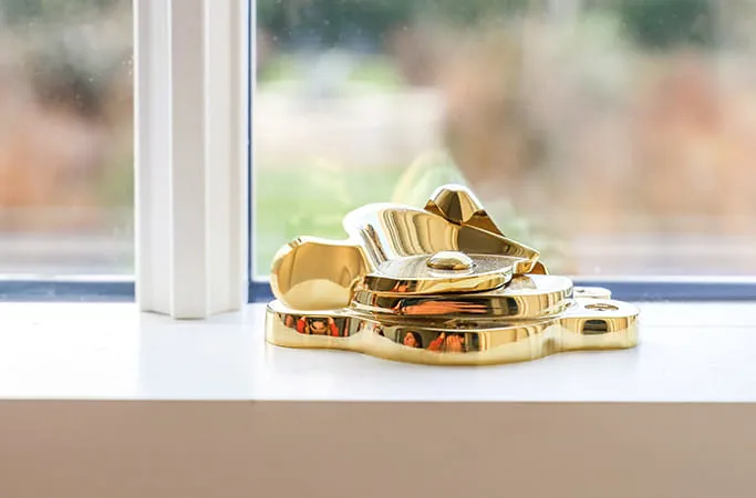 Gold window latch on white windowsill