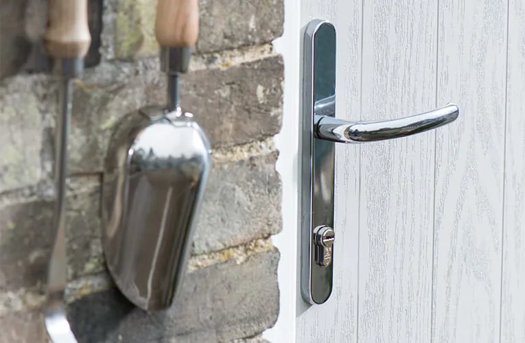 Chrome door handle on a white wood-effect door
