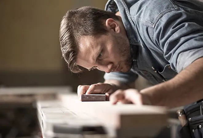 Man sanding wood surface in workshop