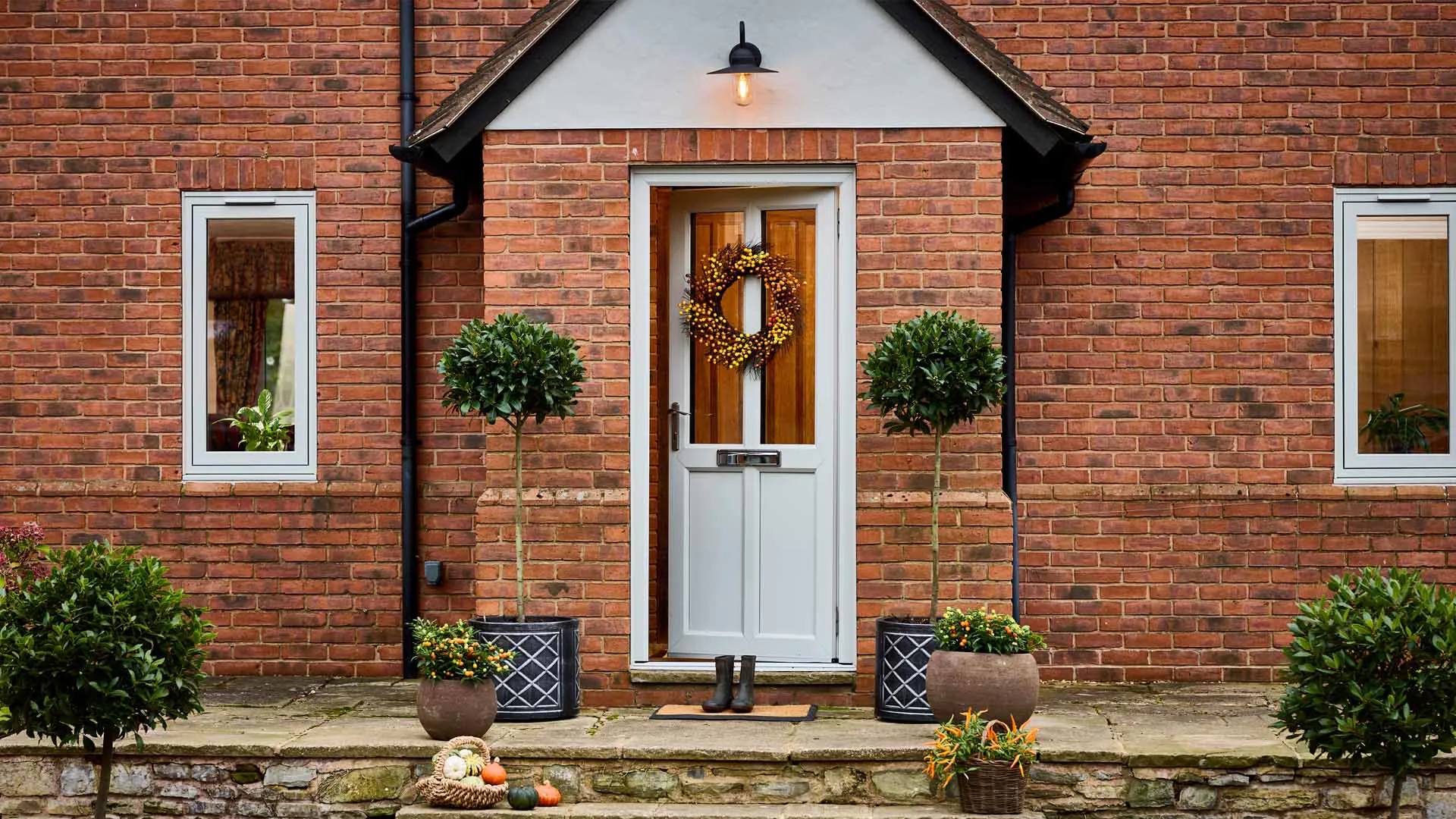 Front door with autumnal wreath and potted plants