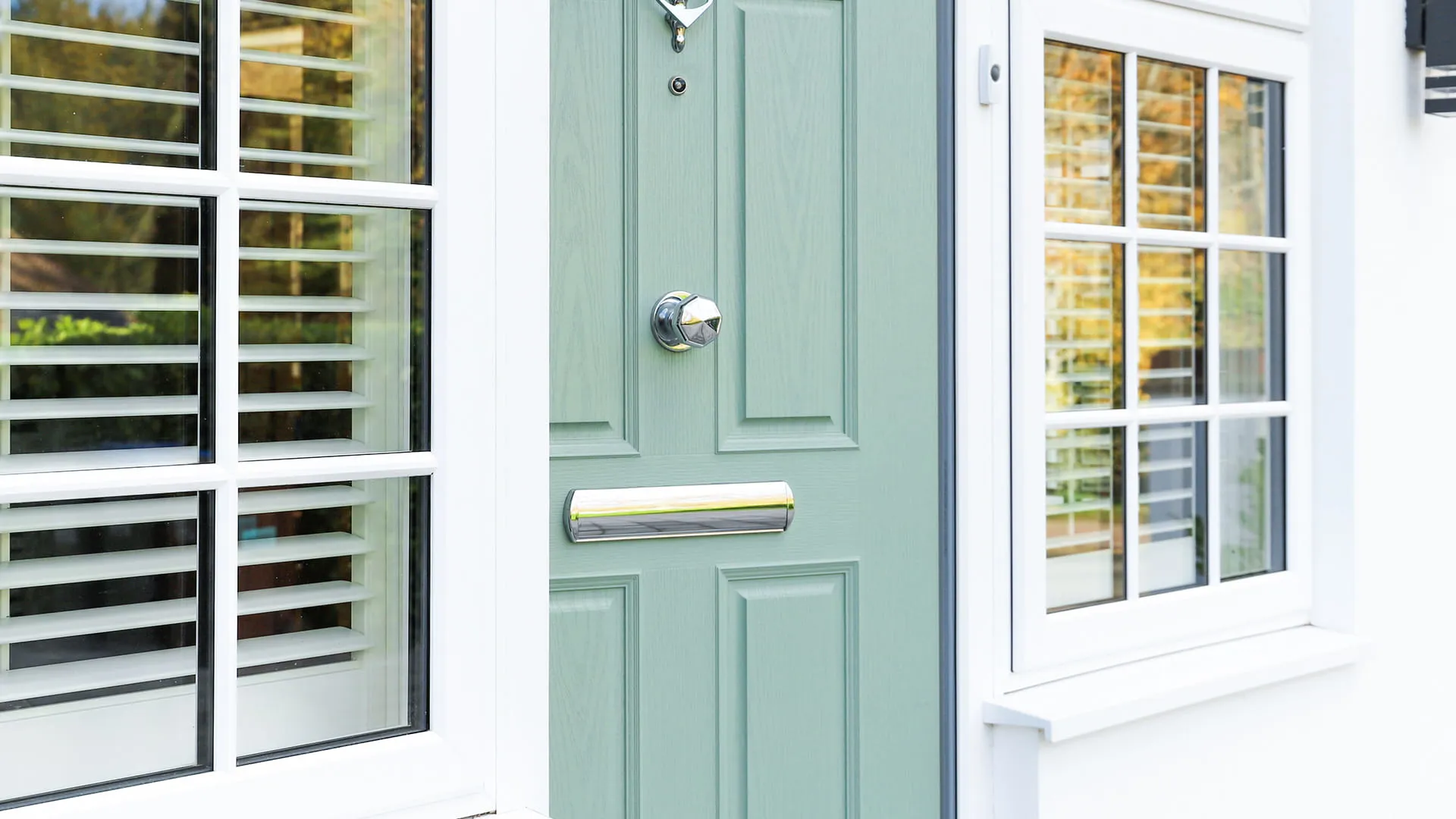 Sage green door with white window and shutters