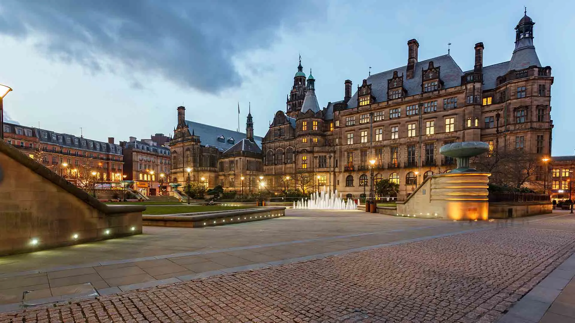 City square at dusk with fountain and buildings