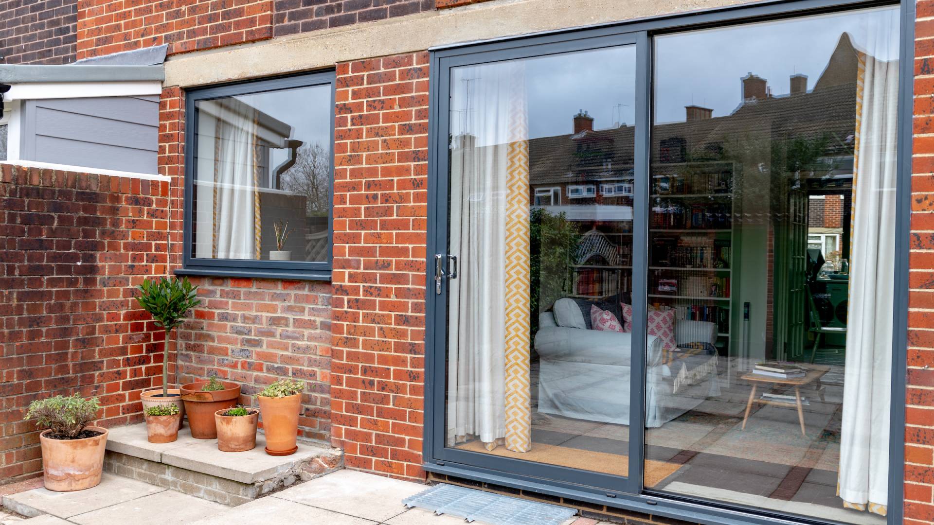 Everest conservatory with gray sliding doors and brick wall
