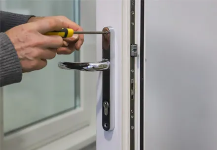 Person fixing a white Everest conservatory door handle with screwdriver