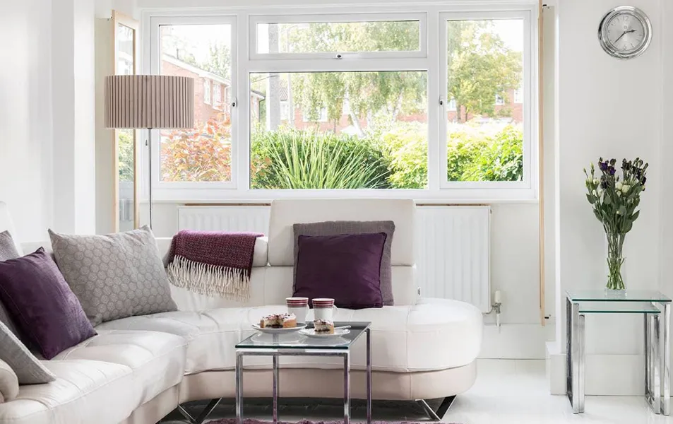 White leather sofa with purple cushions and a glass coffee table