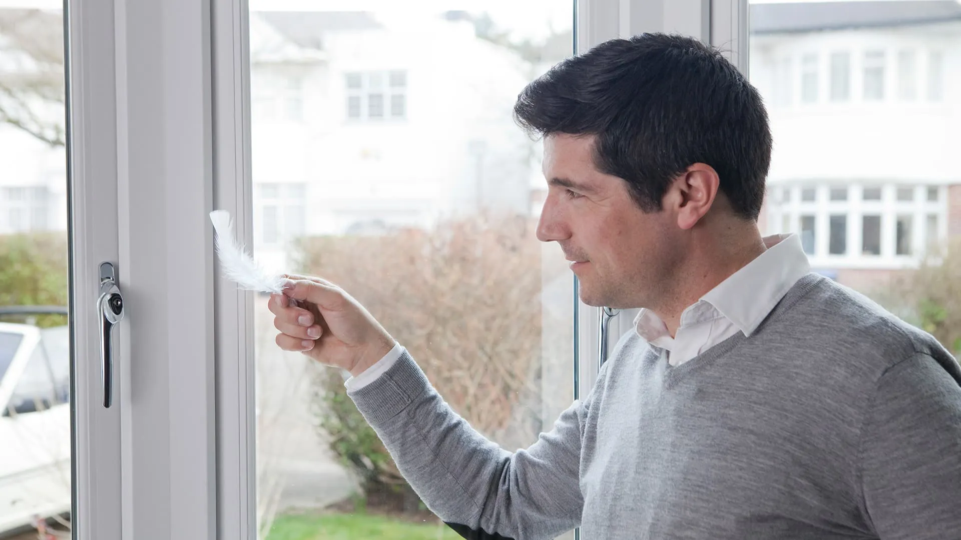 Man checking Everest conservatory window tightness with feather