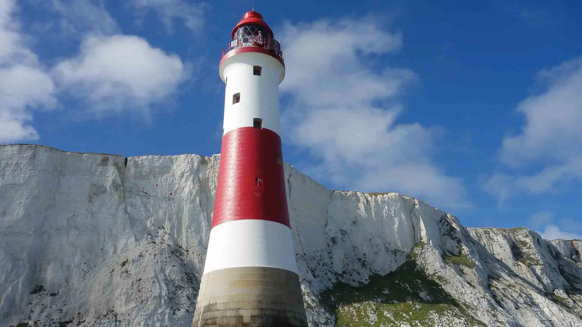 White lighthouse with red bands against white cliffs