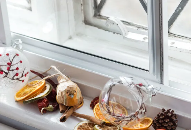 Christmas decorations on windowsill with ornaments, dried citrus, and bird