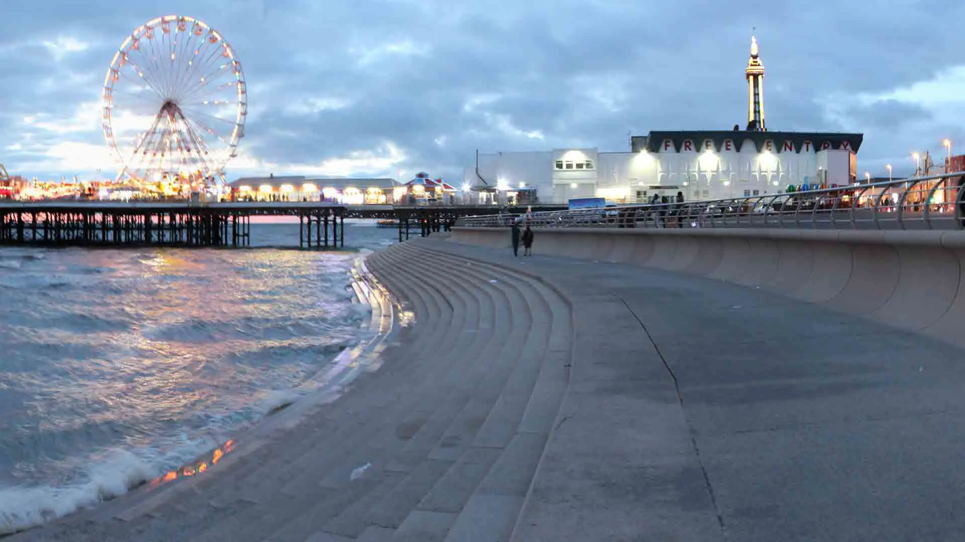 Coastal walkway at night with steps and pier
