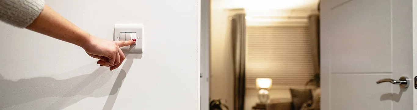 Hand turning on a white light switch