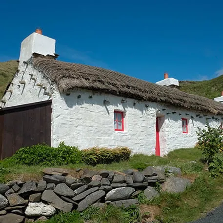 Whitewashed cottage with thatched roof and red windows