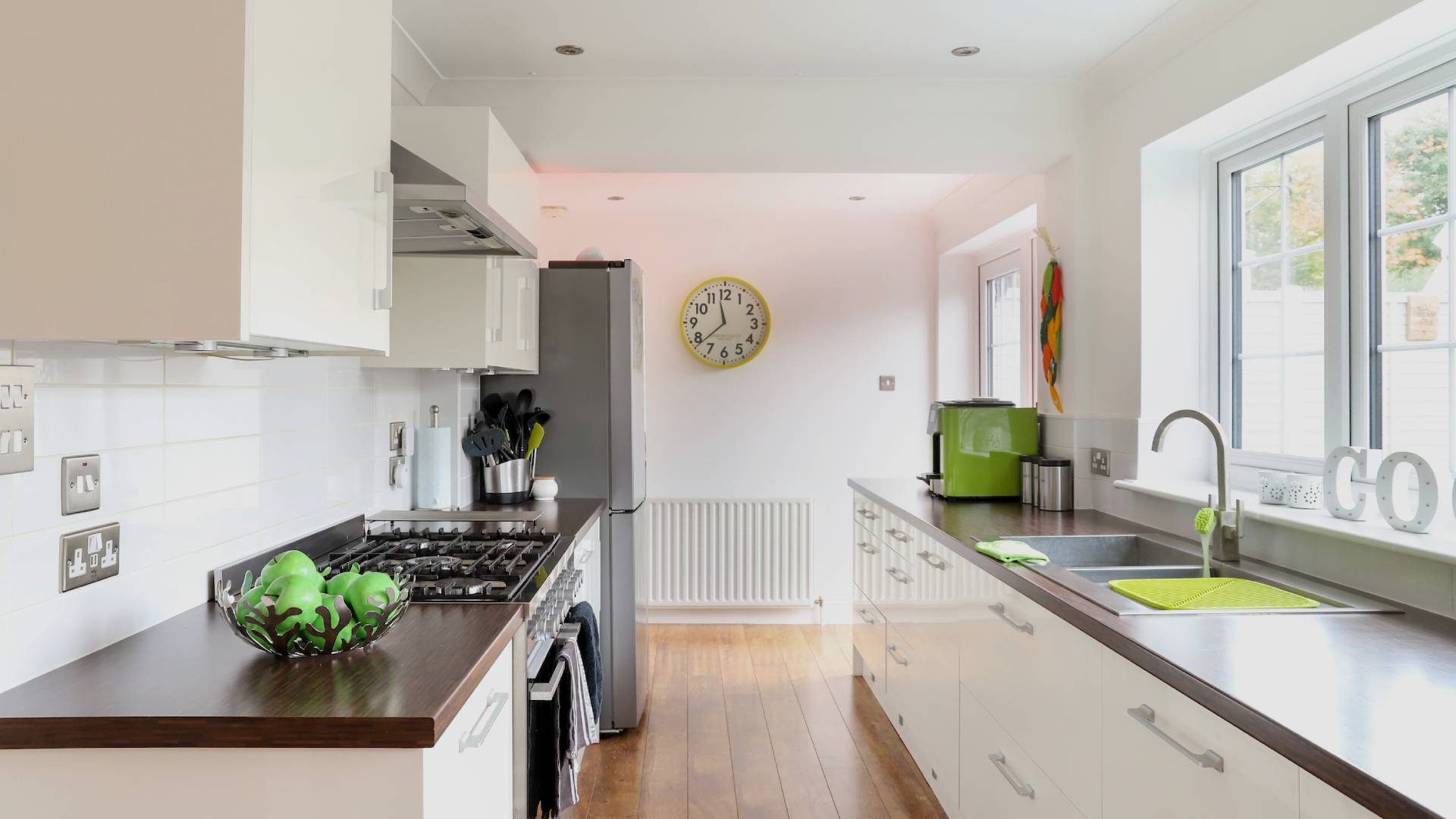 White kitchen with dark brown countertops and green apples in a bowl