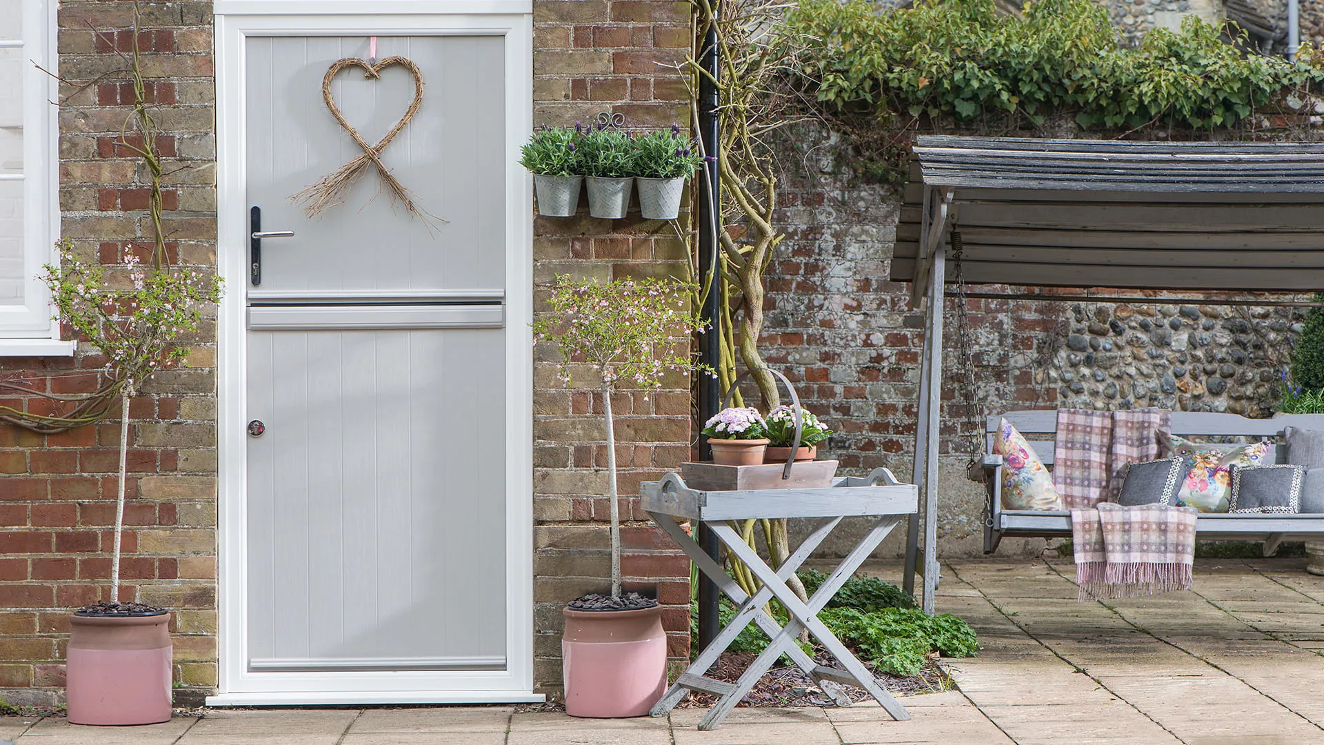 Grey painted door with heart shaped decoration and plants