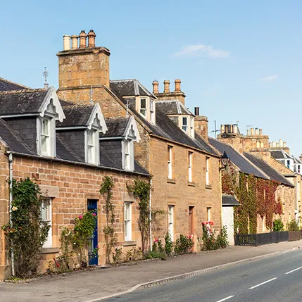 Row of light brown stone houses with dark gray roofs