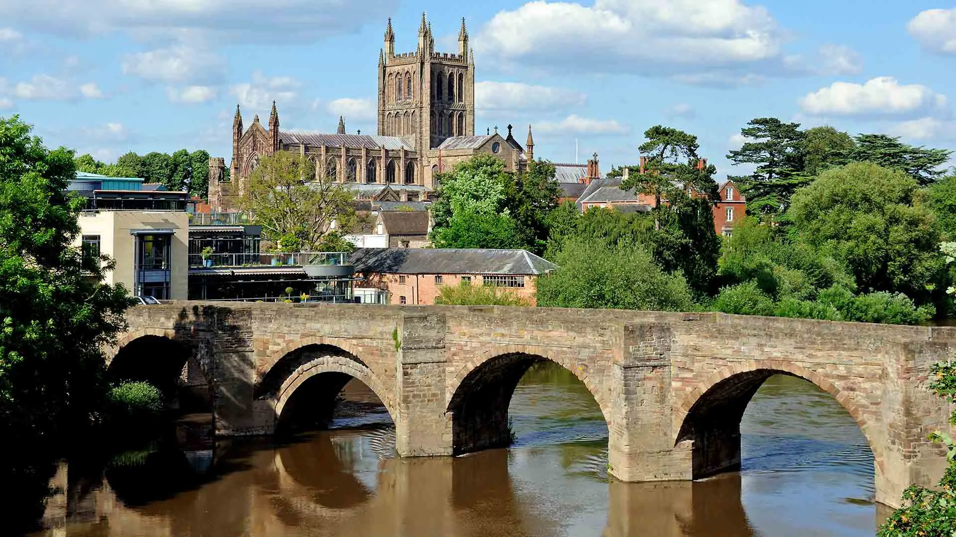 Stone bridge over river with city skyline