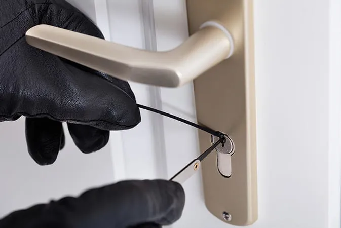 Black gloves picking lock with tools