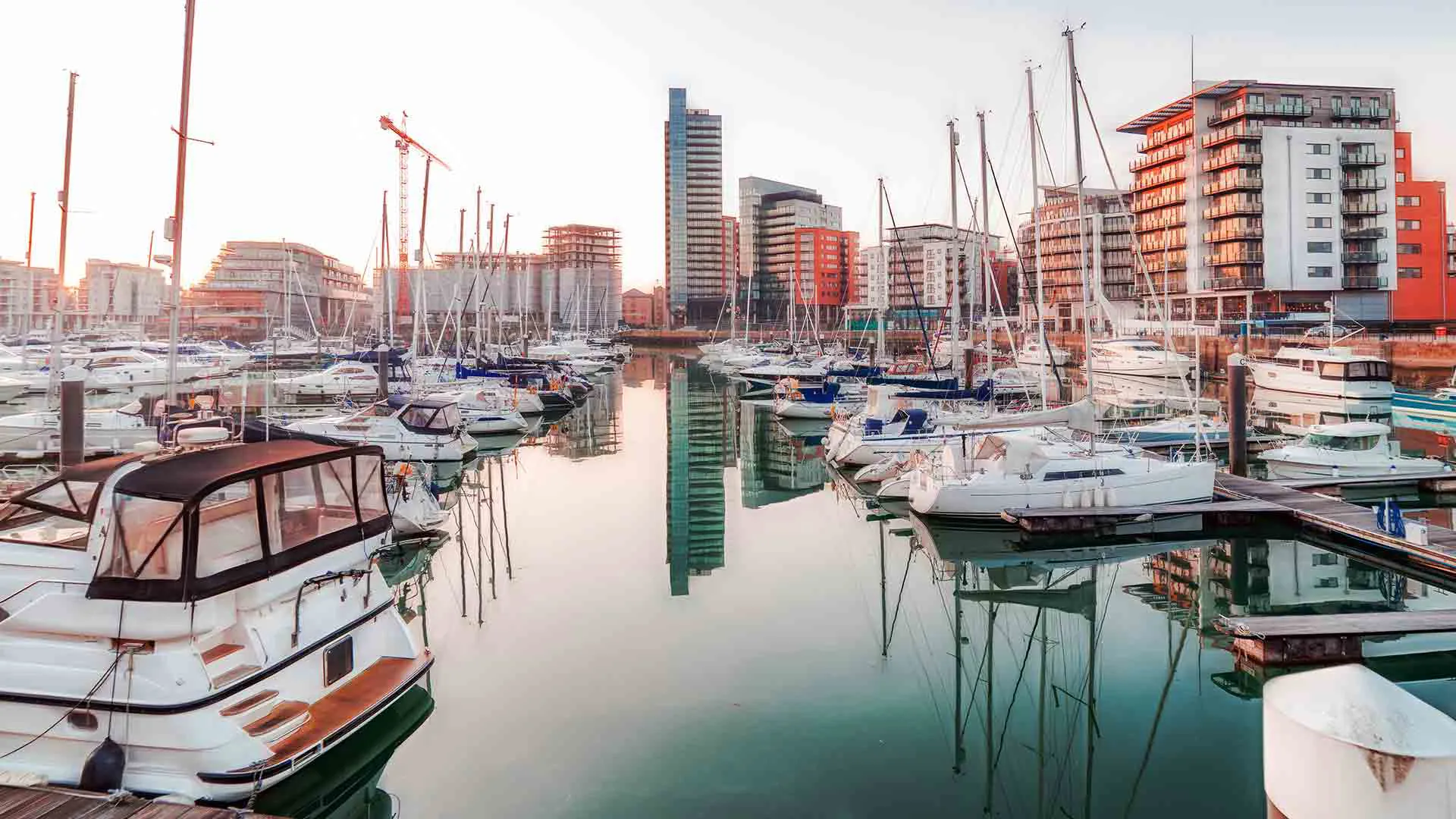 Boats docked in marina with city buildings in background