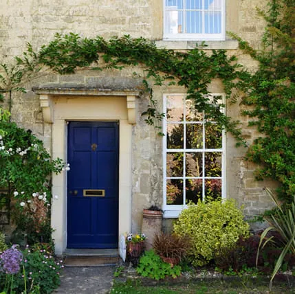 Stone house with blue front door and blooming flowers