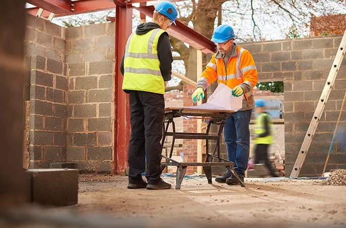 Construction workers reviewing blueprints on site