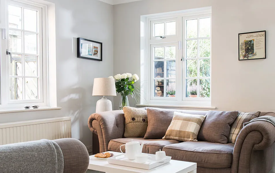 Light brown sofa with white pillows and window