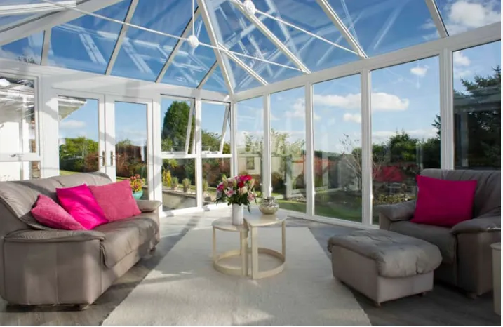 Everest conservatory with gray sofa, pink cushions, and white furniture