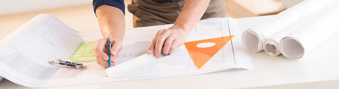 Person reviewing architectural plans with tools