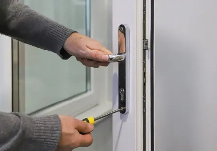 Person fixing a white door handle with screwdriver