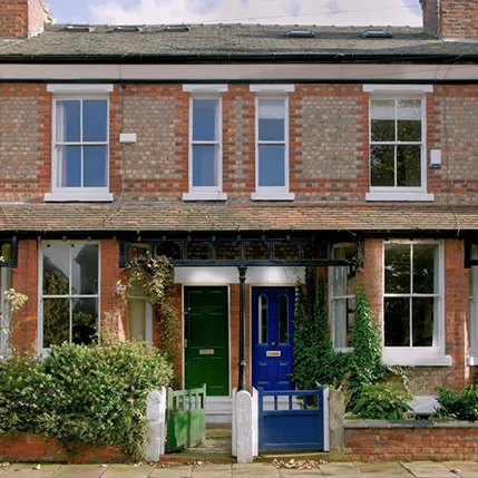 Two green and blue doors on a red brick house