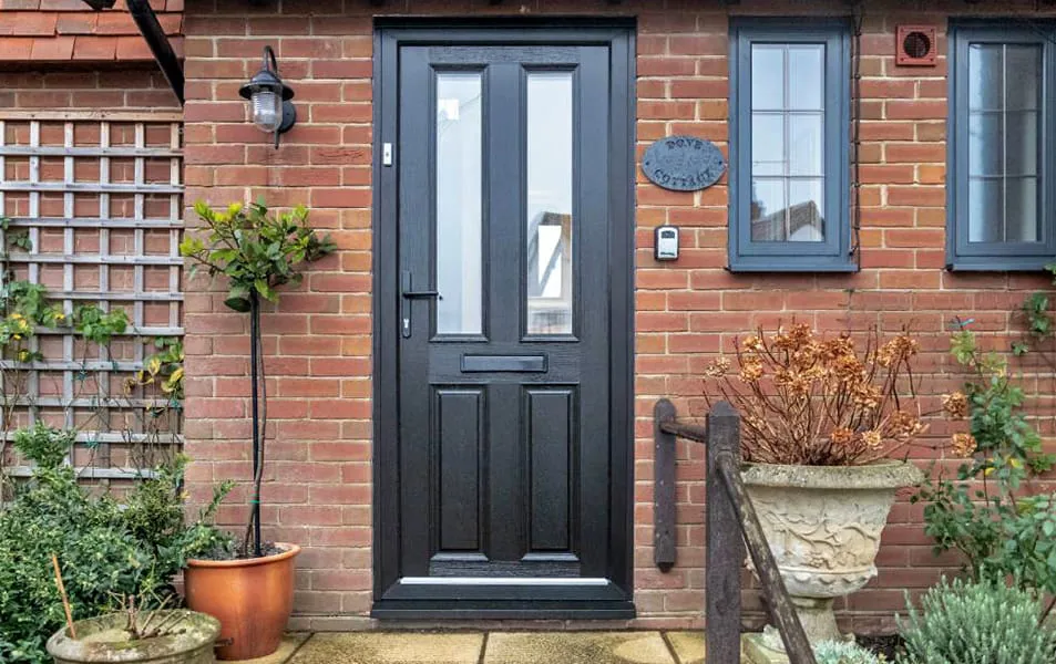 Black exterior door with glass panels on brick wall