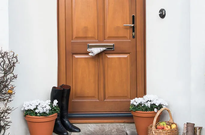 Wooden front door with newspaper in the mailbox
