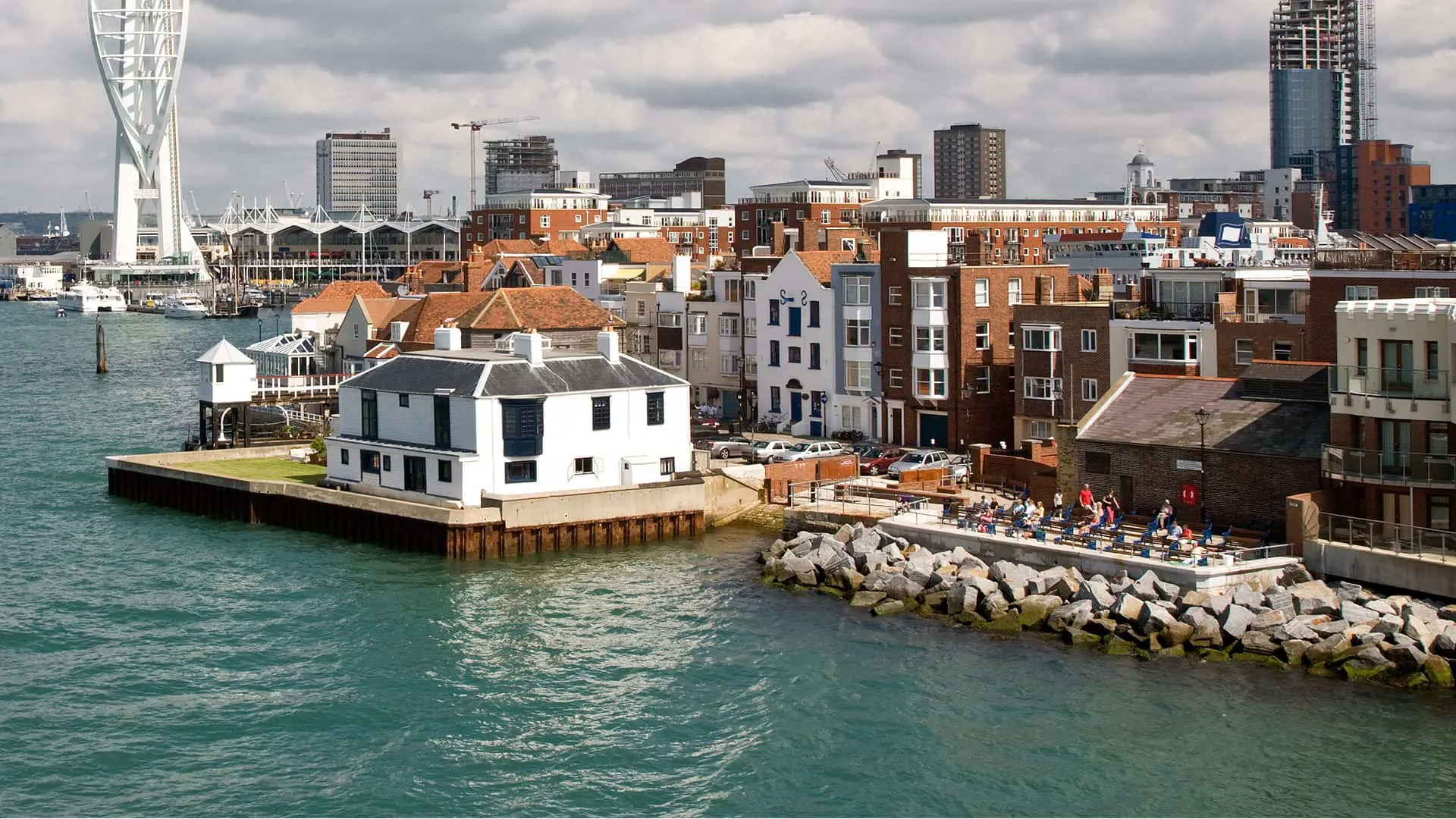 Coastal town scene with white houses and people relaxing by the water