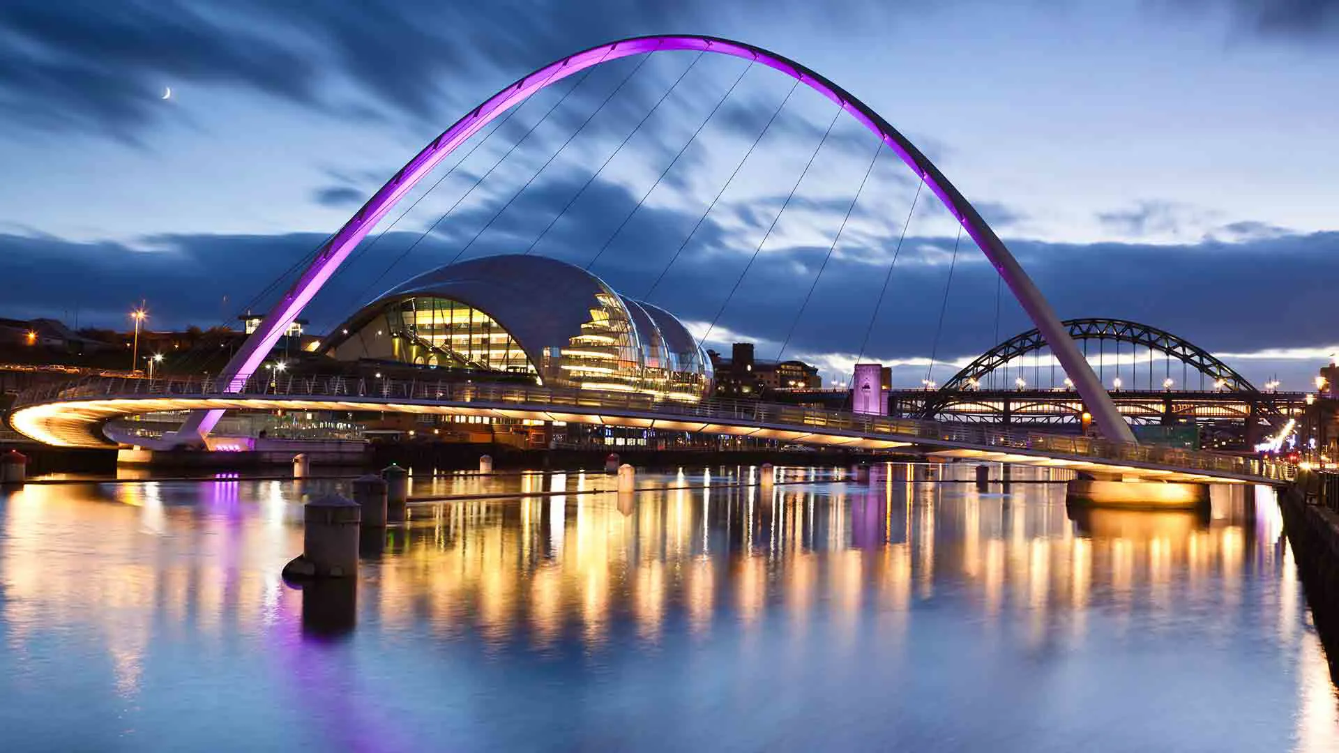 Illuminated bridge at dusk over water