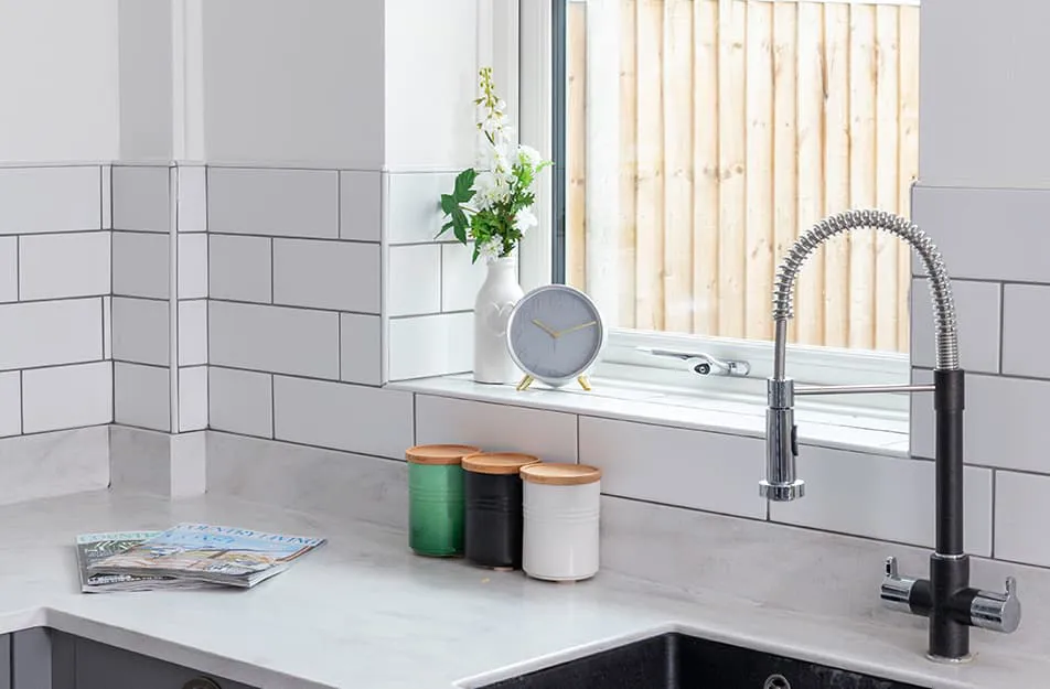 White kitchen with a grey clock, green and white storage containers