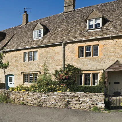 Two light beige stone houses with dark gray slate roofs