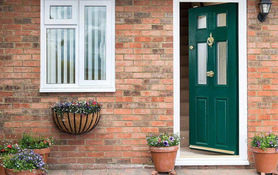 Everest conservatory green door with white trim and brick facade