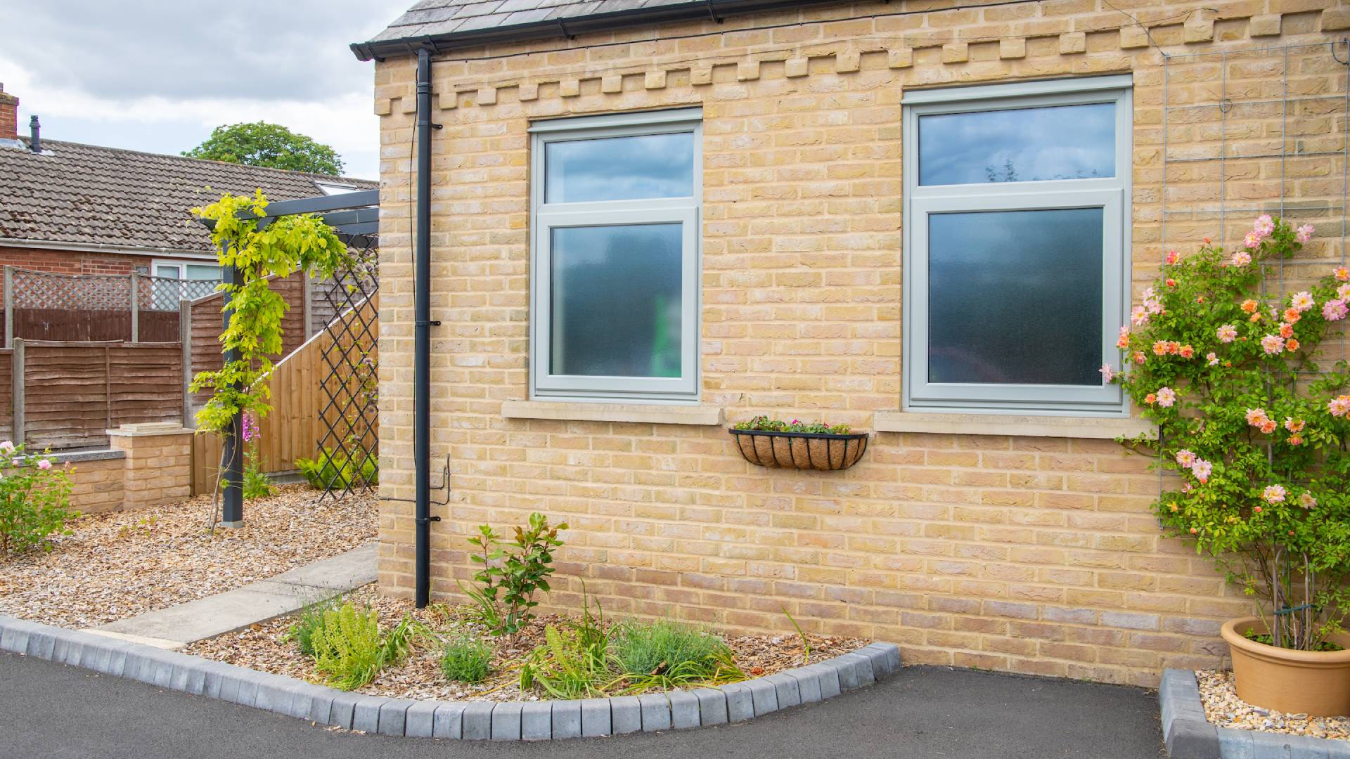 Light gray windows on a tan brick exterior wall with flowers