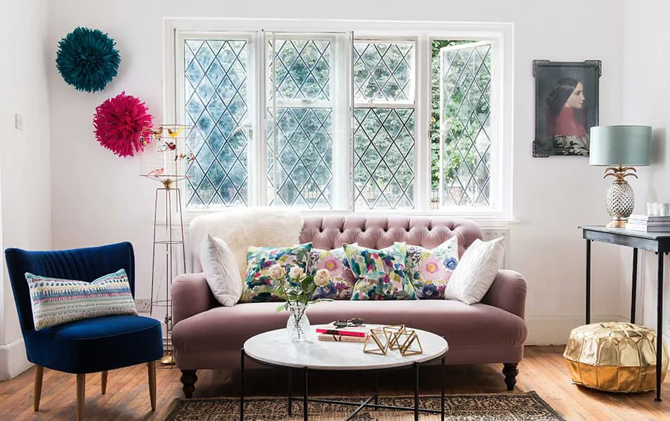 Pink sofa with colorful cushions and accessories in a room