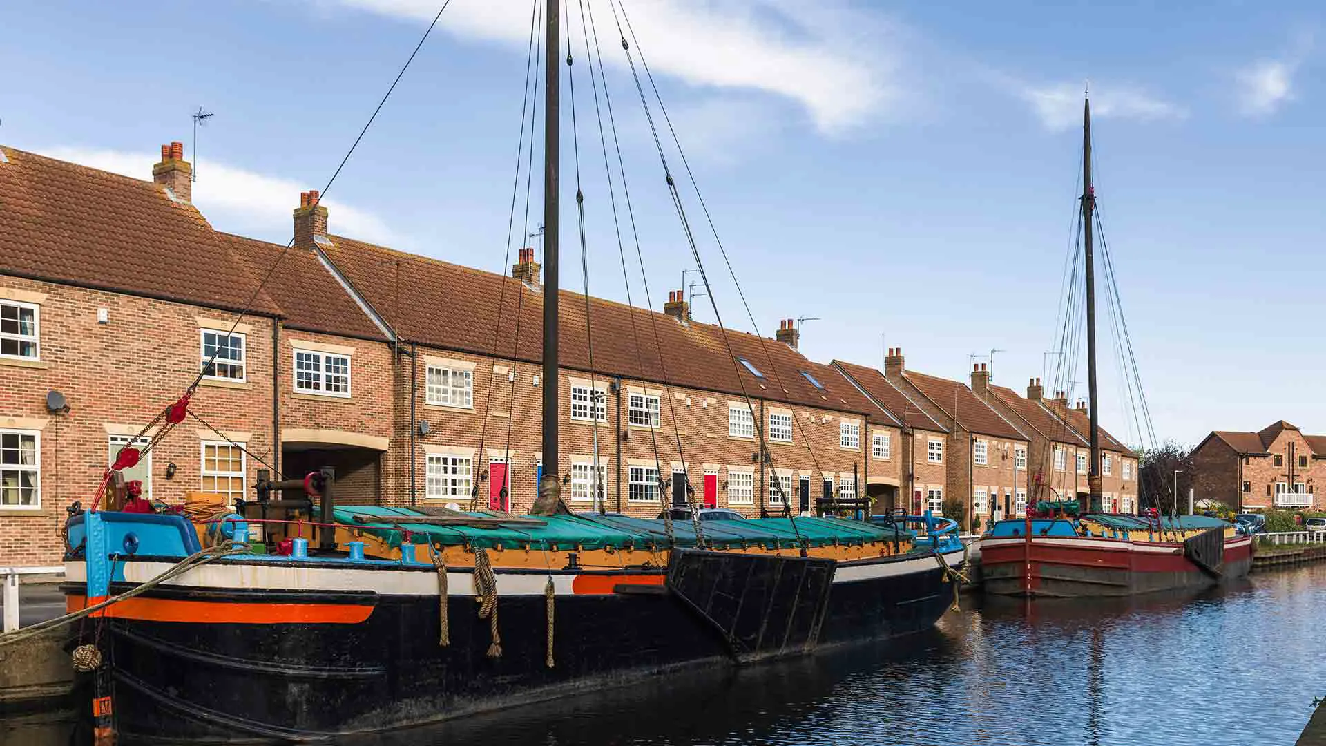 Canal boats moored alongside brick houses