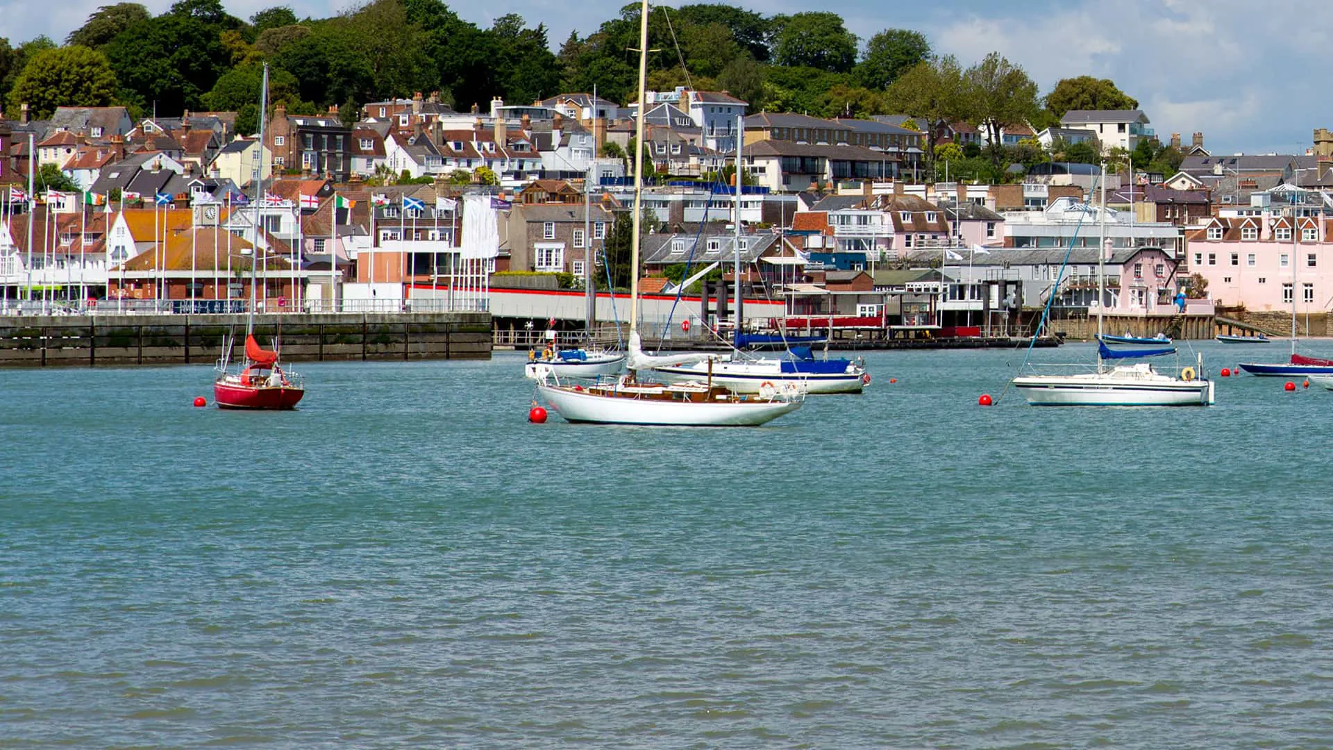 Boats moored in harbour with town in background