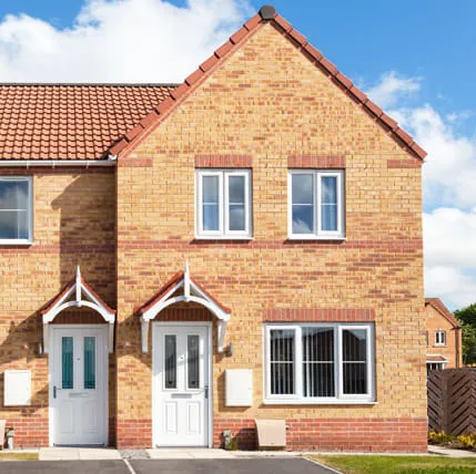 Two storey house with tan bricks and white doors and windows