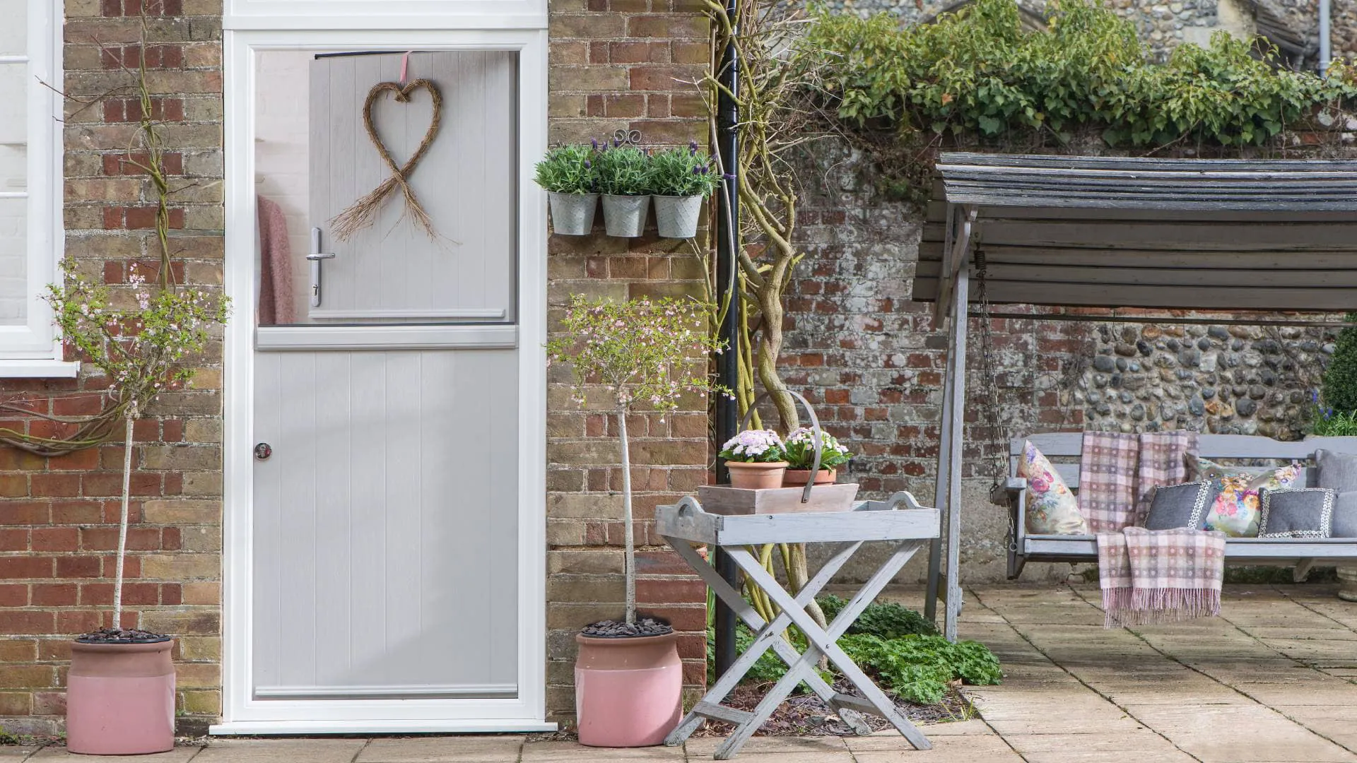 Grey painted door with heart wreath and potted plants