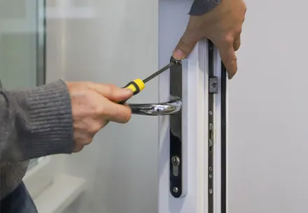 Person repairing a white door handle with screwdriver