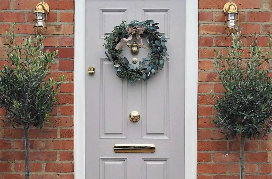 Light gray door with gold wreath and plants