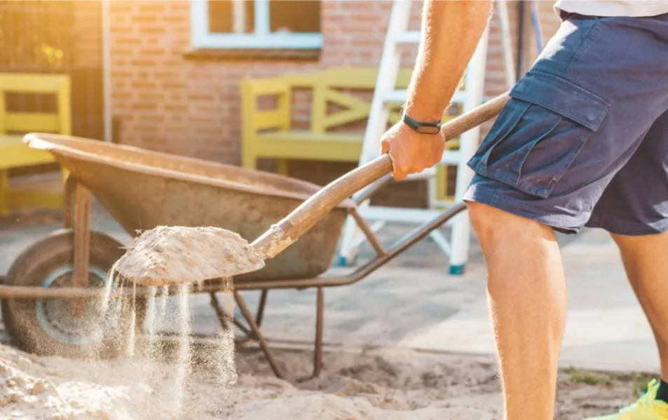 Person loading sand into wheelbarrow