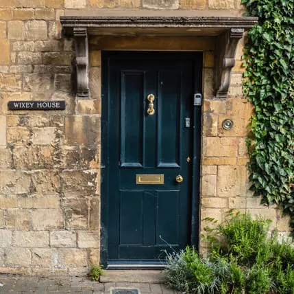 Dark green door with gold hardware on stone wall
