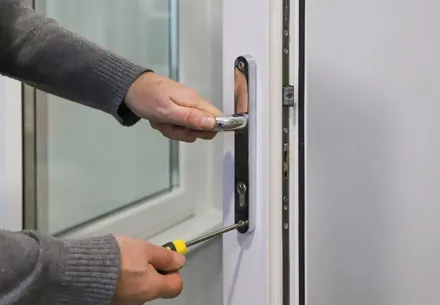 Person fixing a white door handle with screwdriver