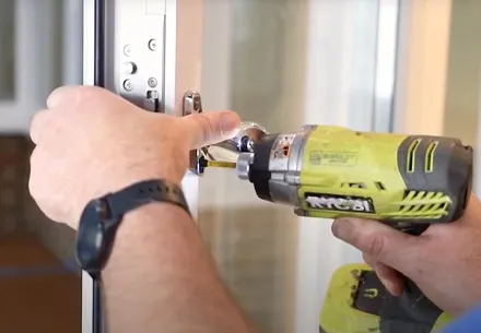 Person installing a door lock with a cordless drill
