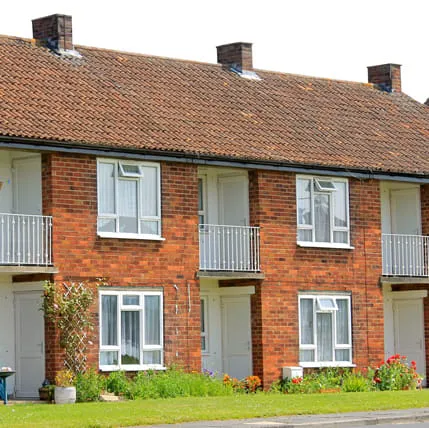 Terracotta roofed brick terraced houses with white windows and railings