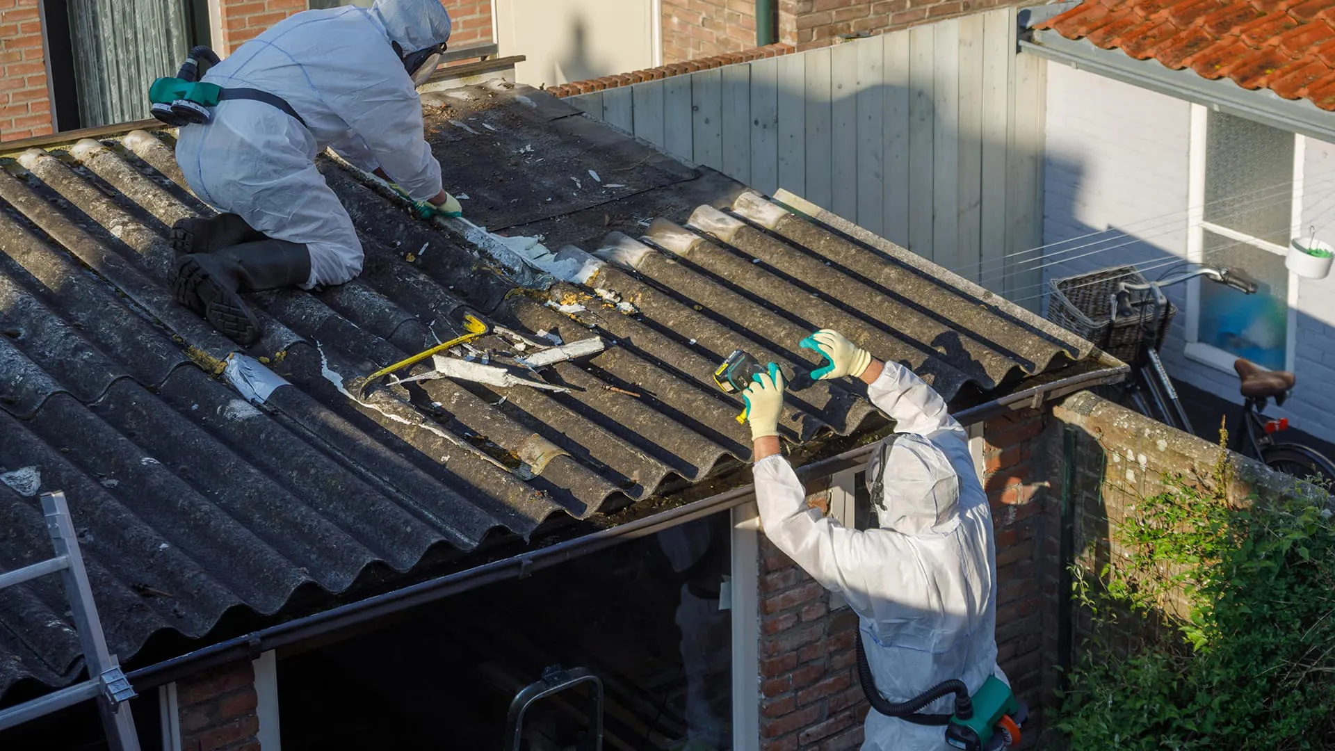 Roofers in protective gear repairing a damaged roof