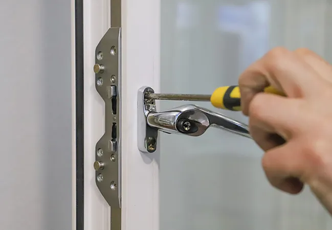 Hand using screwdriver to fix window handle